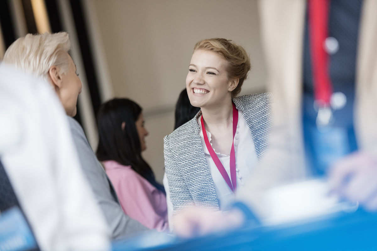 Happy businesswoman talking to colleague at lobby in convention center